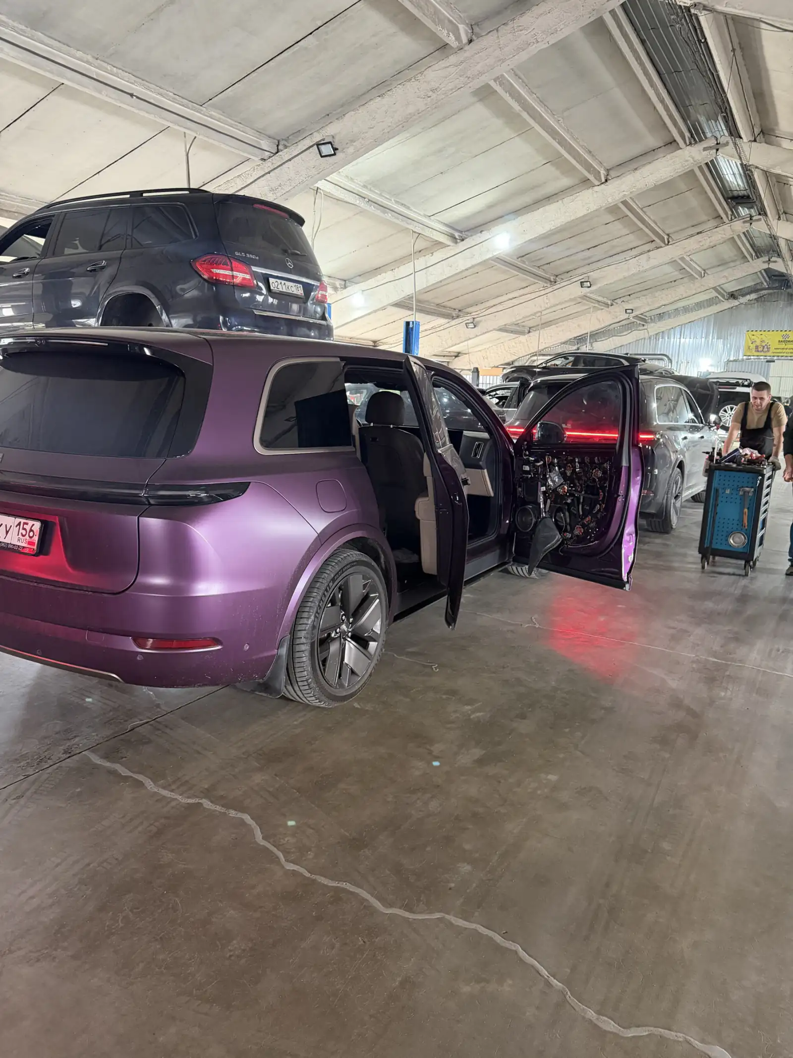 Li Auto в цехе: открытые двери, снятая обшивка, мастер с тележкой инструмента